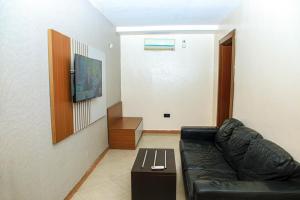 a living room with a black leather couch and a table at Villa Toscana Victoria Island Lagos in Lagos
