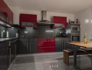 a kitchen with red cabinets and a wooden table at Savanna Loft in Lambsheim