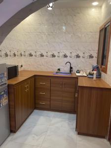 a kitchen with wooden cabinets and a stone wall at Hébergement corniche in Saint-Louis