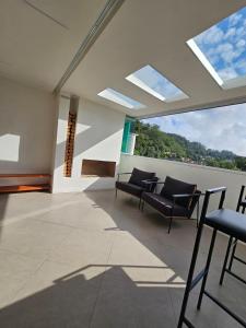 a room with chairs and a table and windows at Cobertura Elegância da Serra in Petrópolis