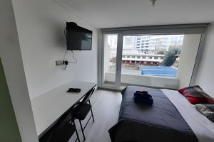 a bedroom with a bed and a desk and a window at Edificio Stepke in Temuco