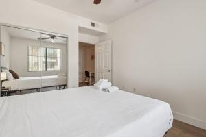Shamrock Mobile Home ParkにあるCozySuites Glendale - Westgate with pool 17の白いベッドルーム(大きな白いベッド1台、鏡付)