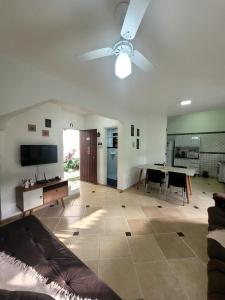 a living room with a ceiling fan and a table at Casa de condomínio em Boicucanga in Boicucanga +37 photos