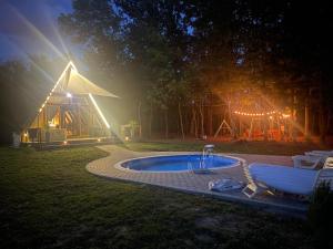 a tent with a hot tub in the yard at night at Dedin borak in Drenovci +19 photos
