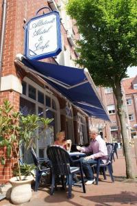 dos personas sentadas en una mesa fuera de un restaurante en Altstadt Hotel Meppen, en Meppen