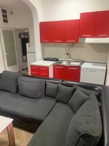 a living room with a couch and a kitchen with red cabinets at Zakovski in Skopje +1 photo