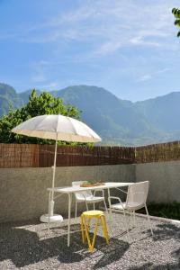ein weißer Tisch, zwei Stühle und ein Regenschirm in der Unterkunft Araça Studio - Atlantic Mountain Living in São Vicente