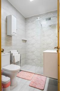 a white bathroom with a shower and a toilet at Moonlight Flower in Mamaia