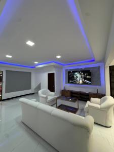 Il comprend un salon doté d'un mobilier blanc et d'une télévision à écran plat. dans l'établissement Casa Viveo, a modern and spacious house!, à San José