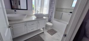 a white bathroom with two sinks and a shower at Hidden Exquisite home in Saint James