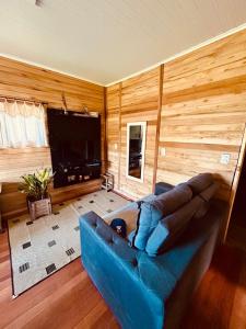 ein blaues Sofa im Wohnzimmer mit TV in der Unterkunft Cantinho aconchegante na Serra in Três Coroas
