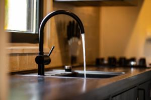a kitchen sink with water running from a faucet at 4pers Welness vakantiehuis in natuurrijke omgeving in Reutum