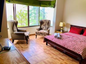 Un dormitorio con una cama grande y dos sillas. en 3 Bed Luxury House with Valley Views & Privacy, en Murree