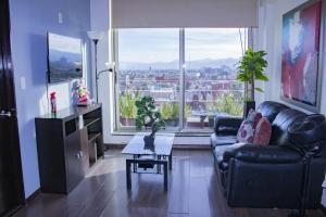 a living room with a couch and a large window at Puerta Alameda Suites México in Mexico City