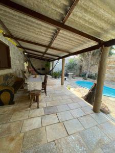 een terras met luifel en een tafel en een zwembad bij Sobrado Beira da Mata in Pirenópolis