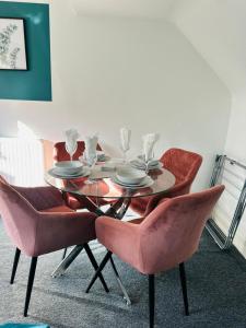 a dining room table with pink chairs and a table with plates at The Residency 4 bed home in Liverpool free parking in Litherland