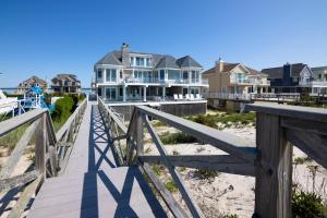 a wooden boardwalk leading to houses on the beach at Spectacular 8 Bedroom Oceanfront Hamptons Beach House, Your Castle By The Sea ! in Remsenburg