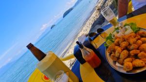 a table with a plate of food and drinks on the beach at A Ver o Mar Guest House in Caraguatatuba