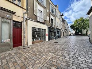 una strada vuota con edifici e una porta rossa di La Mezzanine Bourgogne a Orléans
