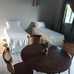 ein Zimmer mit Tisch und Stühlen und zwei Betten in der Unterkunft Ariticum Chalés in Lagoa Sêca