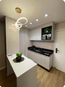 a kitchen with white cabinets and a white counter top at Studio Flat Cuiabá in Cuiabá