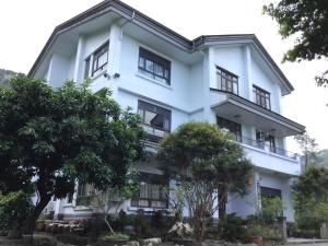 埔里闕麒景觀民宿Chill Villa B&B的一栋白色建筑，前面有树