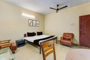 a bedroom with a bed and a chair and a table at Super Collection O Nanmangalam Lake Formerly Vasantham Guest House in Chennai