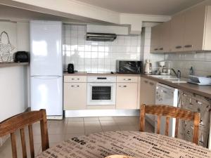 a kitchen with a white refrigerator and a table and chairs at 1-bedroom apartment with view of private beach in Agon Coutainville