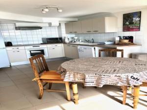 a kitchen with a table and two chairs and a kitchen with white cabinets at 1-bedroom apartment with view of private beach in Agon Coutainville