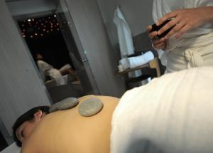 a man with rocks on his stomach in a room at The Ziba Hotel & Spa in Peschiera del Garda