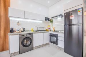 a kitchen with a refrigerator and a washing machine at Cactus Apartment - Walk to Surf Beaches, Rooftop View, Remote Work, Free Parking, AC in Agadir nʼ Aït Sa