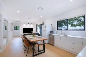une cuisine et une salle à manger avec une table et une cuisine avec des placards blancs dans l'établissement The Terrarena - Family Stay near Shopping & Eateries, à Brisbane