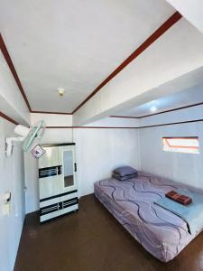 a small bedroom with a bed and a refrigerator at Medya homestay in Pulau Sarang