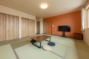 a large room with a table and a tv at 遊学の宿いさみや 