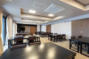 a conference room with tables and chairs and a screen at 遊学の宿いさみや 