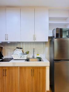 a kitchen with white cabinets and a stainless steel refrigerator at Relaxing Escape with Spacious Sofa Corner in Mandurriao