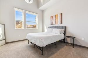 a white bedroom with a bed and two windows at CozySuites PHX RORO Gym Pool Pets & Parking #15 in Phoenix