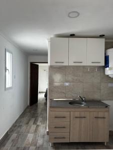 Una cocina con fregadero y gabinetes blancos. en Departamento en Claromeco, en Balneario Claromecó