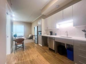 a kitchen with white cabinets and a table and a chair at 415 Modern Brand New Studio Apartment in East Spotswood