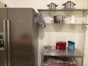 Una cocina con refrigerador y un estante con ollas y sartenes. en Akrata Haven, en Akráta