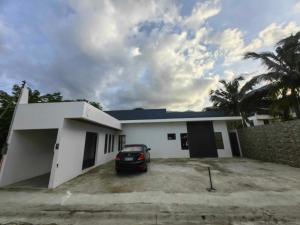 a white house with a car parked in a driveway at Aura Spring Resort in Los Baños