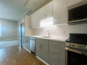 a kitchen with white cabinets and a sink at 403 Modern Brand New Studio Apartment in East Spotswood
