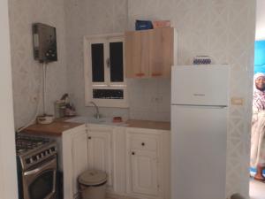 una cucina con mobili bianchi e un frigorifero bianco di Jamila1 a Taguermess