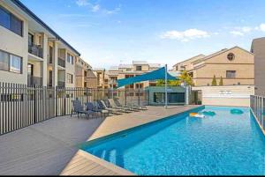 パースにあるEast Perth modern 2 Bedroom with Pool & parkingのアパートメントの建物の前にスイミングプールがあります。