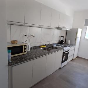 a kitchen with white cabinets and a sink and a microwave at Departamento moderno a estrenar Santo Tomé, Santa Fe in Santo Tomé