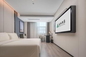 a hotel room with a bed and a flat screen tv at Spring Hotel Shenzhen Bao'an International Airport in Shenzhen
