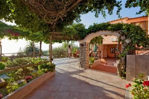 a garden with an arbor and a person walking on a patio at Hotel Il Girasole in Anacapri