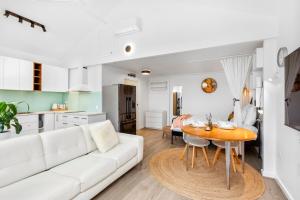 a living room with a white couch and a table at Bees Knees Studio, 5 min to CBD, Adelaide Airport & Henley Beach in Thebarton