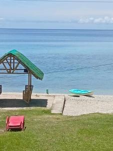 a bench and a boat on the beach at Evashore Beach Resort in Limasawa Island