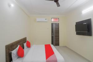 a bedroom with a bed with red pillows and a tv at HOTEL O R.K. INN in Gorakhpur